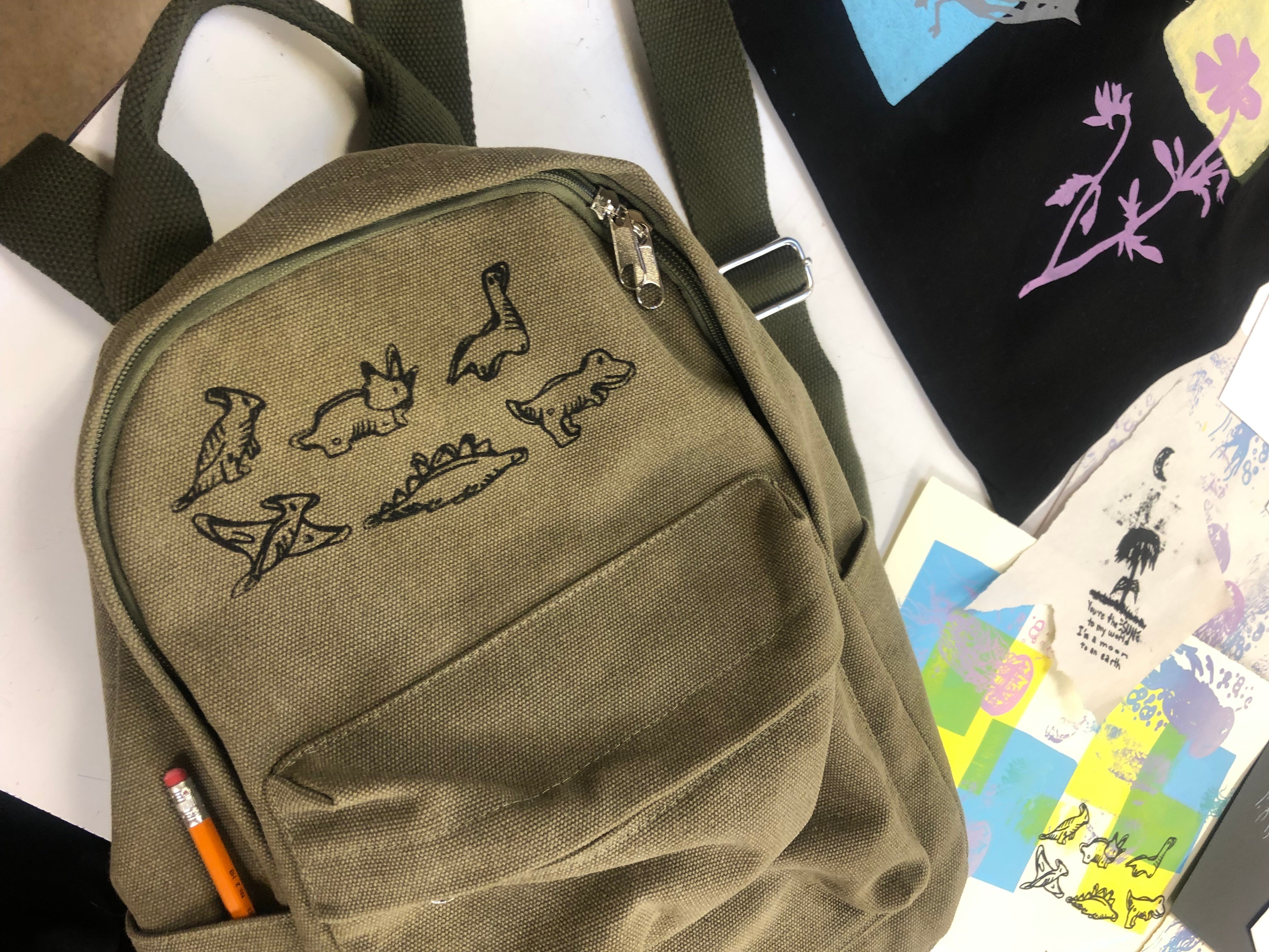 A backpack with a student-made screen-printed dinosaur design on it