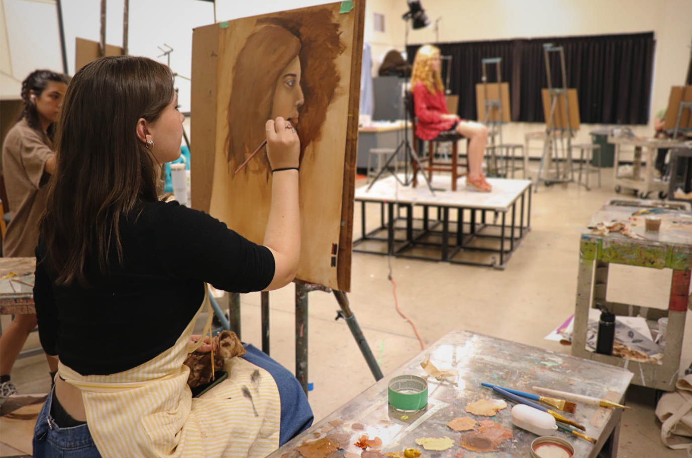 A student paints the portrait of a model