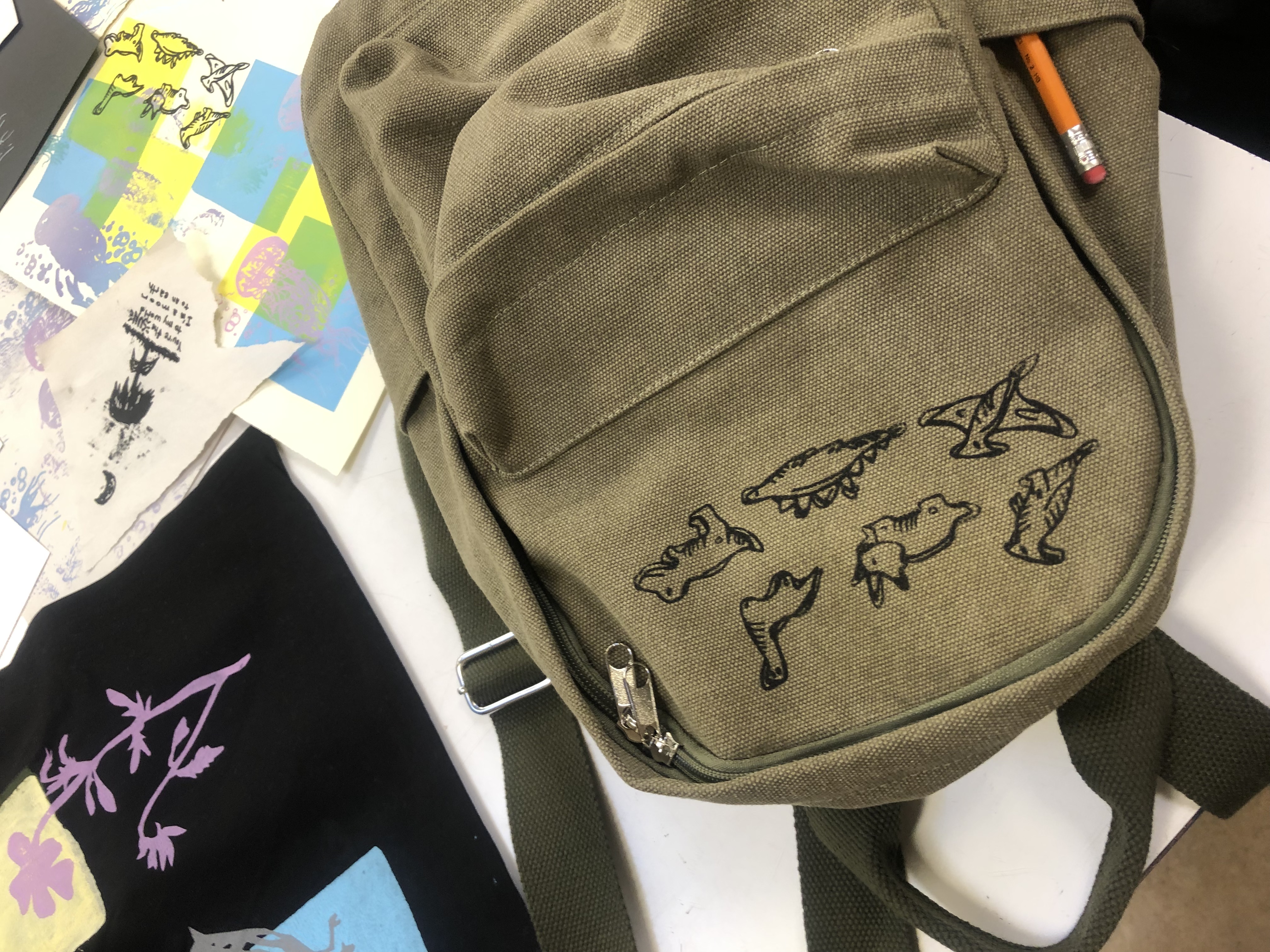 A backpack with a student-made screen-printed dinosaur design on it